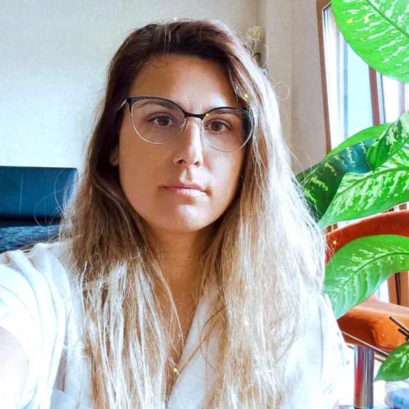 Portrait at home, next to a large green plant.